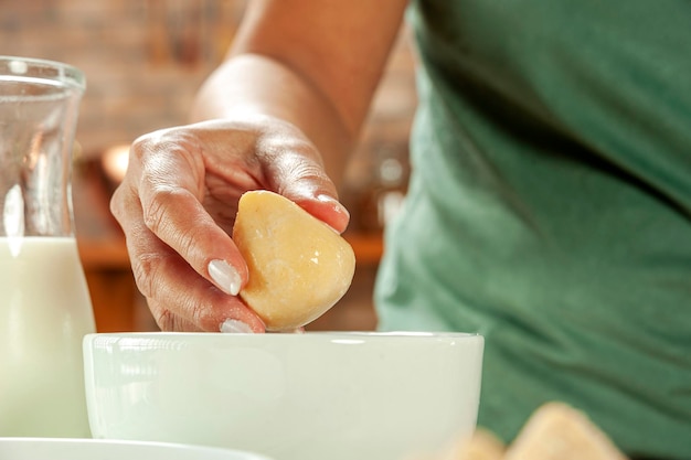 Frauenhände panieren brasilianische Krokette Coxinha de Frango mit Semmelbröseln auf einem hölzernen Küchentisch