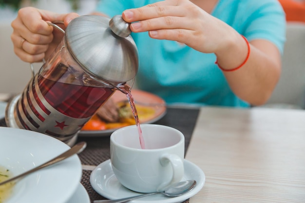 Foto frauenhände schließen das gießen von früchtetee aus dem wasserkocher. französische presse