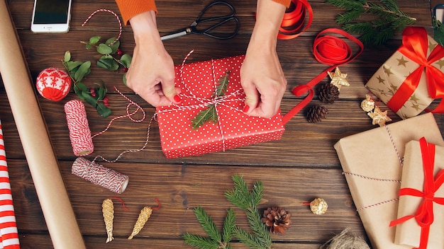 Frauenhände schmücken die Geschenkbox. Weihnachtskomposition auf Vor einem dunklen Hintergrund