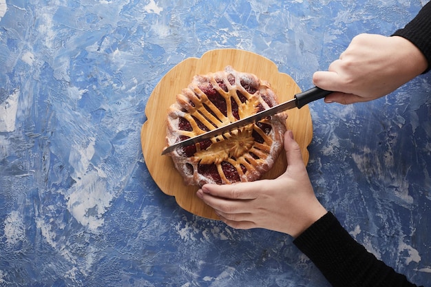 Frauenhände schneiden einen klassischen amerikanischen Kuchen mit einem Messer