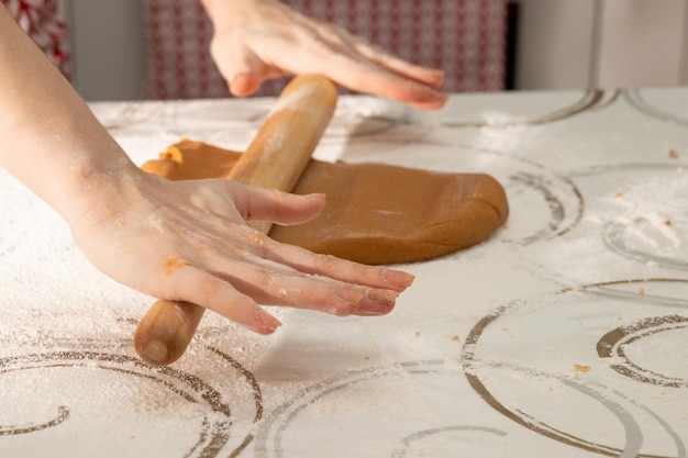 Frauenhände schneiden Formen zum Backen von Lebkuchenplätzchen aus