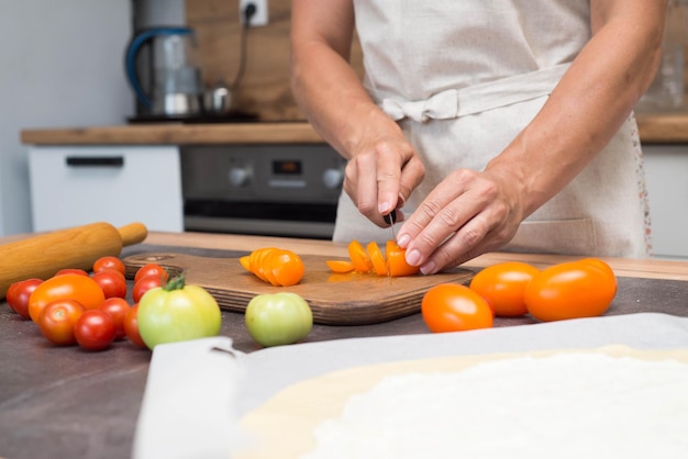Frauenhände schneiden Tomaten auf Scheiben Zubereitung von Pizza