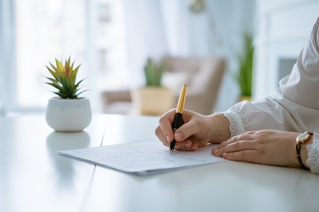 Frauenhände schreiben auf Blatt mit einem Stift Hände der Geschäftsfrau, die mit Dokumenten arbeitet