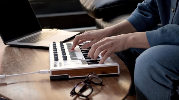 Foto frauenhände spielen auf kleinem midi-controller musikproduzent mit laptop auf dem tisch nahaufnahme von händen, die auf tasten spielen heimstudio mit professioneller ausrüstung