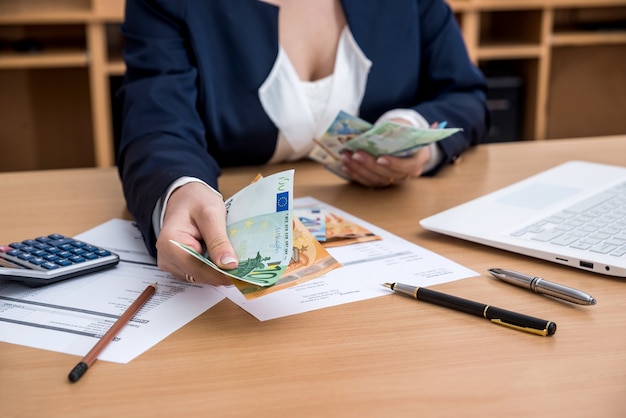 Frauenhände zählen Euro-Geld mit Dokumenten-Haushalts-Laptop-Stift und Taschenrechner