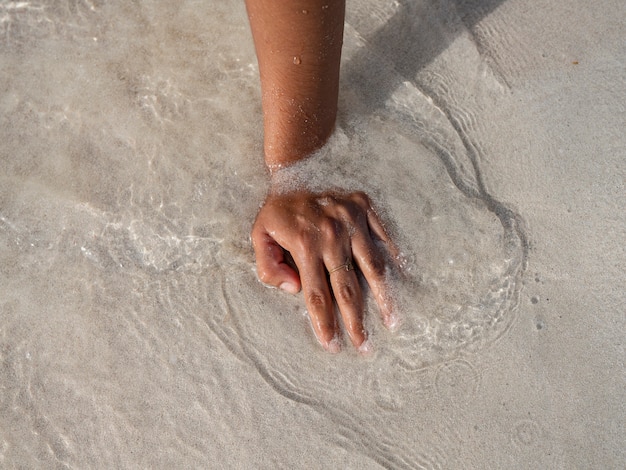 Frauenhand auf Strandsand, Sommerkonzept