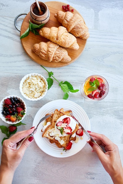 Frauenhand beim Frühstück mit French Toast mit Erdbeeren