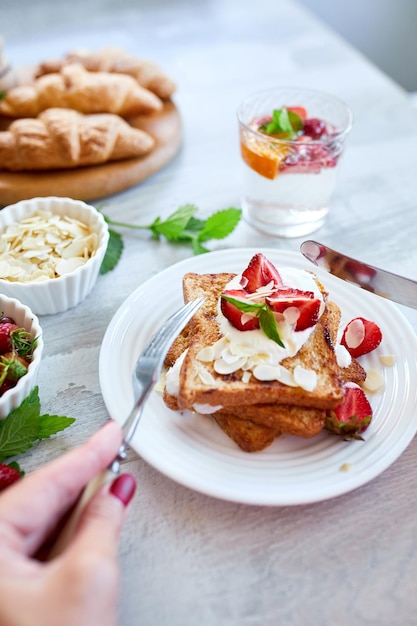 Frauenhand beim Frühstück mit French Toast mit Erdbeeren