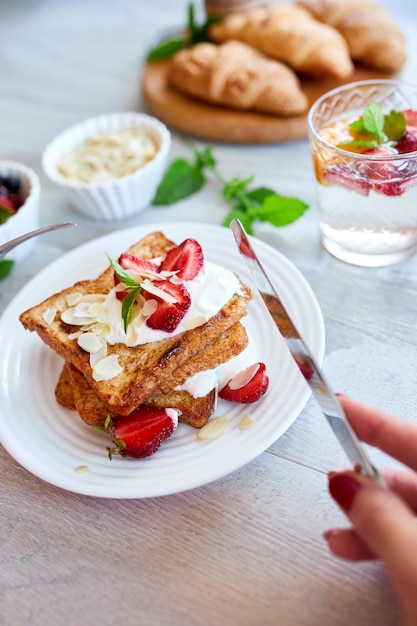 Frauenhand beim Frühstück mit French Toast mit Erdbeeren