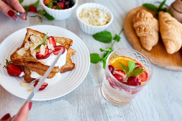 Frauenhand beim Frühstück mit French Toast mit Erdbeeren