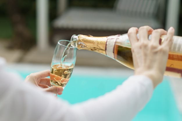 Frauenhand, die Champagner in ein Glas gießt.