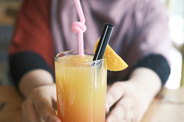 Frauenhand, die ein Glas Orangensaft hält