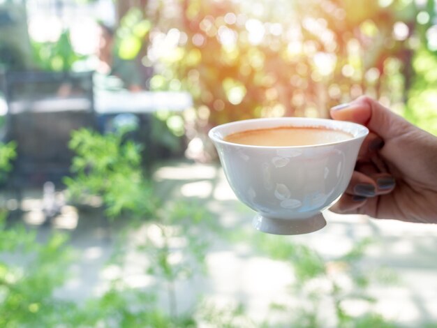 Frauenhand, die eine weiße heiße Kaffeetasse hält