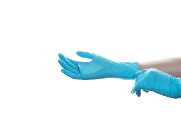Frauenhand, die einen blauen medizinischen Gummihandschuh auf weißer isolierter Wand trägt