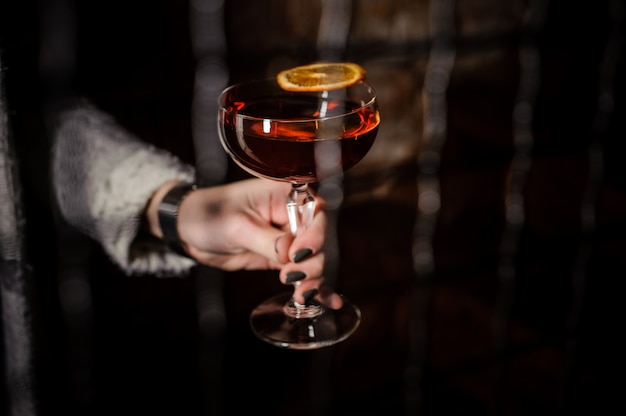 Frauenhand, die einen Manhattan-Cocktail hält