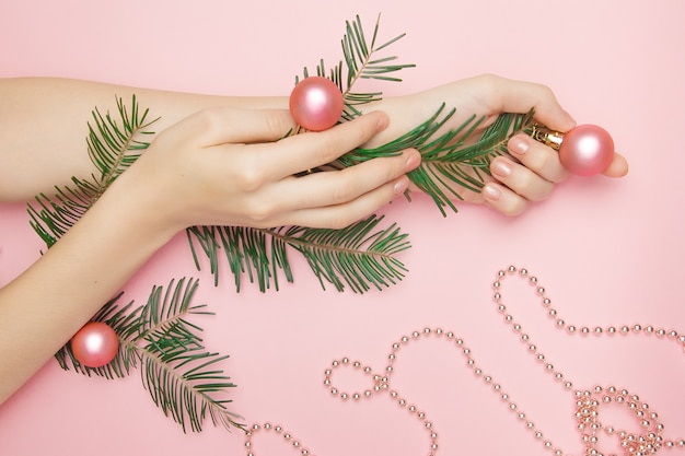 Frauenhand, die einen Zweig mit rosa Kugeln hält