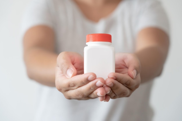 Frauenhand, die freien Platz der weißen Flasche für Textgesundheitswesen und medizinisches Konzept hält