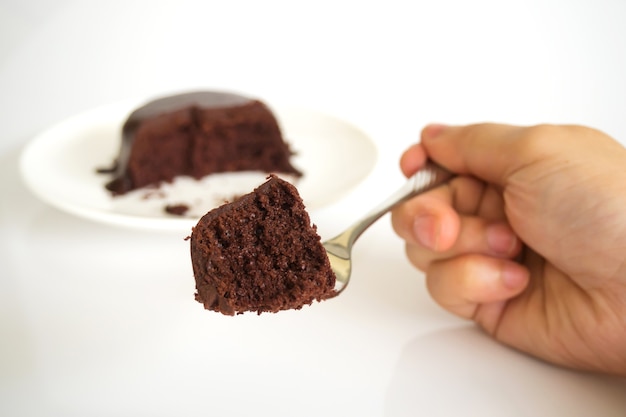 Frauenhand, die Gabel hält, diente Schokoladenkuchen mit Schokoladenfondant