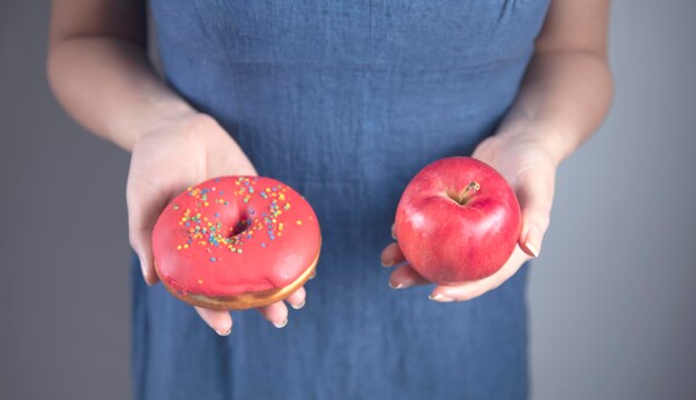 Frauenhand, die Krapfen und Apfel hält