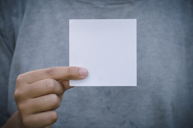 Frauenhand, die leeres Papier auf Naturhintergrund hält.