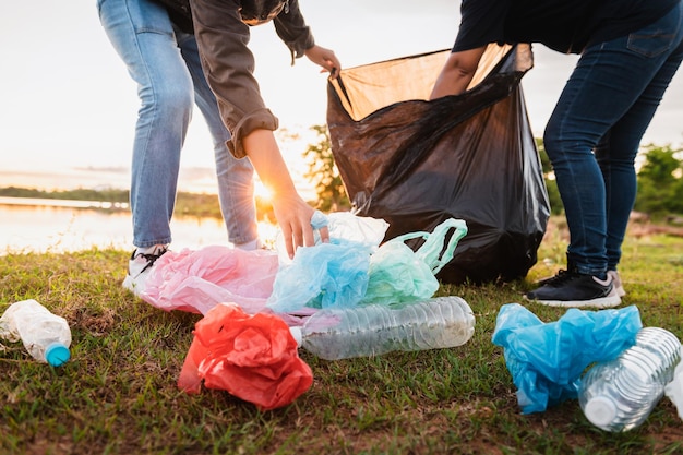 Frauenhand, die Müllplastiktüte zur Reinigung im Park aufhebt