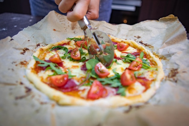 Frauenhand, die Pizza für Stücke schneidet