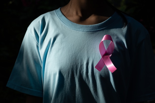 Frauenhand, die rosa Bandbrustkrebsbewusstsein hält. Konzept Gesundheitswesen und Medizin. Krebs-Konzept