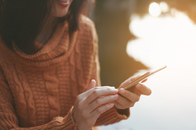 Frauenhand, die Smartphone verwendet, um Arbeit Geschäft, soziales Netzwerk, Kommunikation im öffentlichen Café Arbeitsbereich zu erledigen.