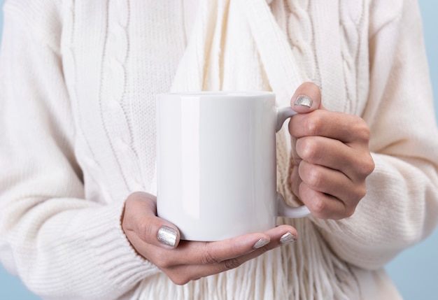 Frauenhand, die weiße keramische Kaffeetasse hält. Modell für kreative Werbetextnachrichten oder Werbeinhalte.