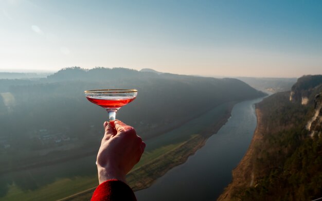 Frauenhand hält ein Glas Champagner an der Elbe in der sächsischen Schweiz