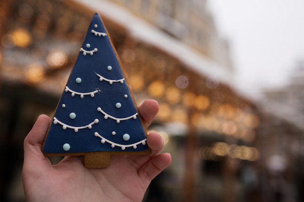 Frauenhand hält Lebkuchen auf dem Weihnachtsmarkt vor dem Hintergrund von Bokeh