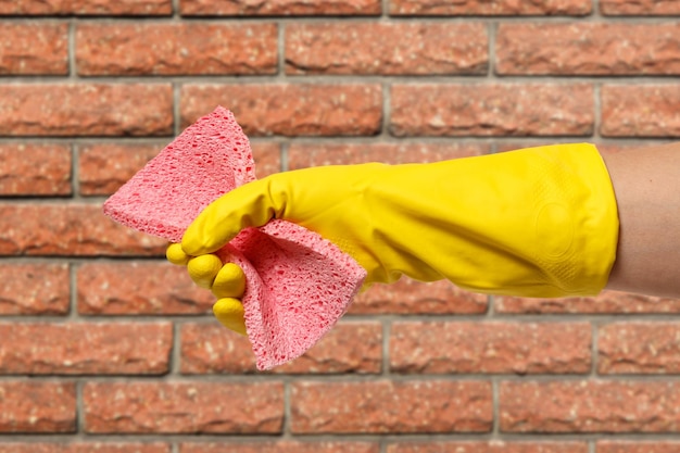 Frauenhand im Schutzhandschuh mit Schwamm