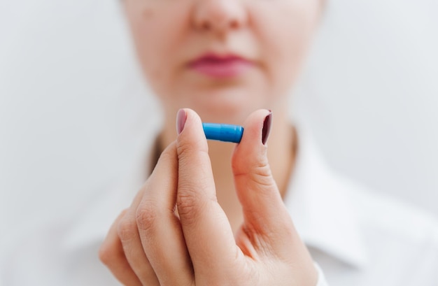 Frauenhand mit blauer Pille Vitaminkapsel Medizinisches Behandlungskonzept der Krankenversicherung