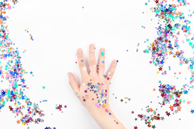 Frauenhand mit festlichen Farbsternkonfettis