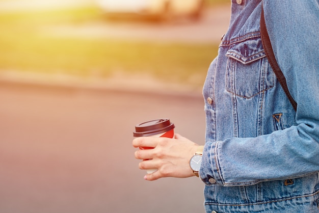 Frauenhand mit Papiertasse kaffee nehmen in einer Stadtstraße weg