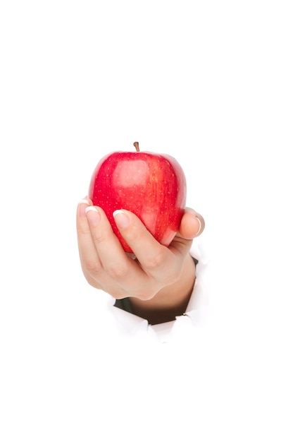 Frauenhand mit rotem Apfel durch ein Loch im Papier isoliert auf weißem Hintergrund