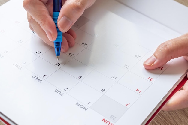 Frauenhand mit Stift schreiben auf Kalenderdatum Geschäftsplanung Termin Meeting Konzept