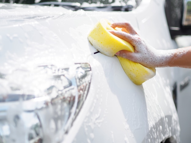 Frauenhand mit waschendem Auto des gelben Schwammes.