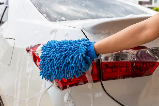 Frauenhand mit waschendem modernem Auto des Rücklichts des blauen microfiber Gewebes oder Reinigungsautomobil.