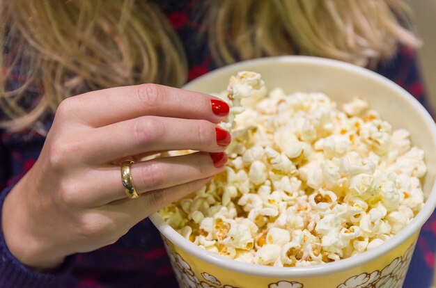 Frauenhand nah oben, Popcorn aufnehmend.