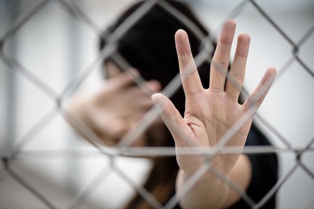 Frauenhand schließt ihr Gesicht und ein anderes Handzeichen für den Halt, der Gewalt missbraucht