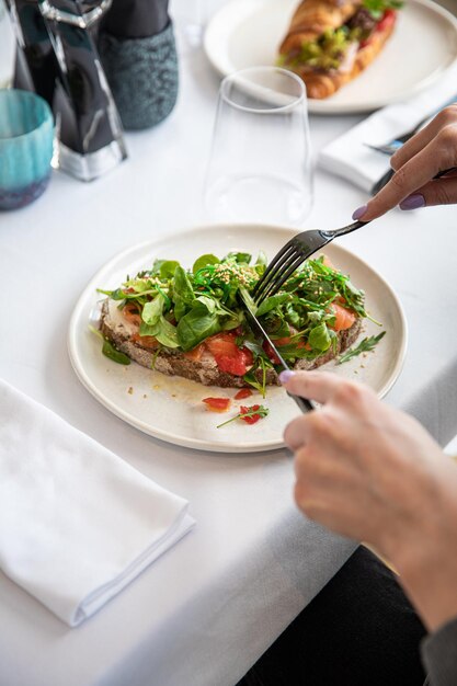 Frauenhand- und -gemüsesalat mit grünem kopfsalatsalat lokalisiert auf weißer platte