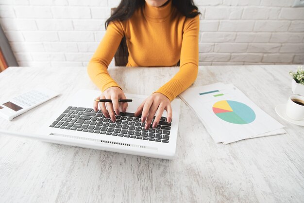 Frauenhandgraph mit Computer auf Tabelle