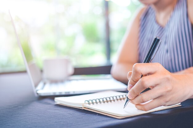 Frauenhandschrift auf Notizblock mit einem Stift im Büro