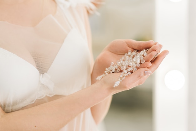 Frauenhochzeitsschmuck (Ohrringe) in den Händen der Braut, selektiver Fokus