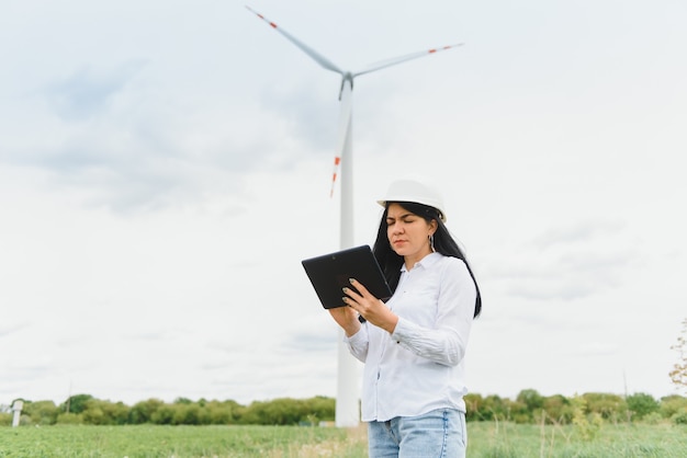 Fraueningenieur, der Tablette für die Arbeit vor Ort im Windkraftanlagenpark verwendet