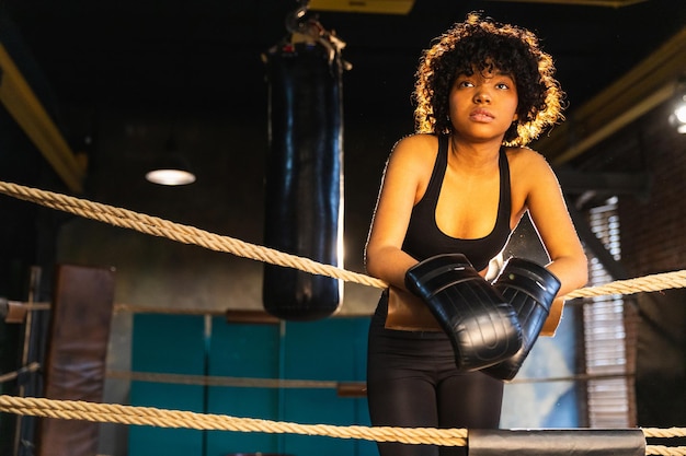 Frauenkämpferin Girl Power Afroamerikanerfrauenkämpferin mit Boxhandschuhen, die auf Boxring l stehen