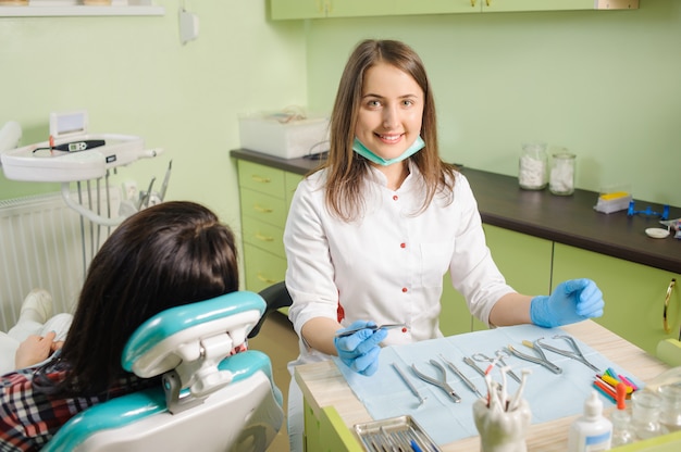 Frauenkieferorthopäde, der zahnmedizinisches Gerät für das Reparieren von Zähnen hält