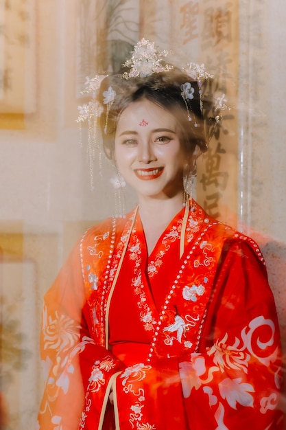 Frauenkleidung China Neujahrsporträt einer Frau in traditioneller Kleidung Frau in traditionelle Kleidung Schöne junge Frau in einem leuchtend roten Kleid und einer Krone der chinesischen Königin posiert