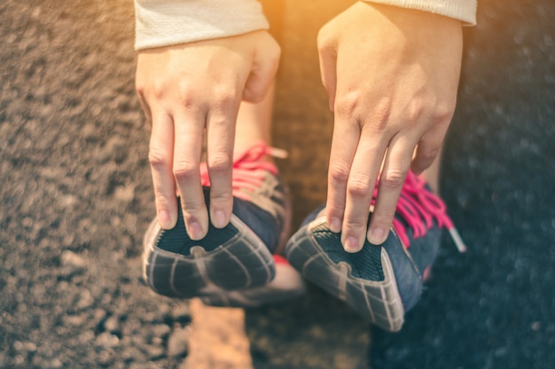 Frauenläuferfüße auf Straße im Trainings-Wellness-Konzept.